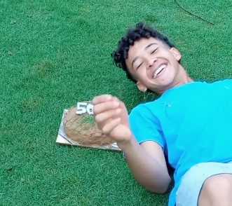 Vitor deitado ao lado do bolo de terra | Foto: Captura de Tela